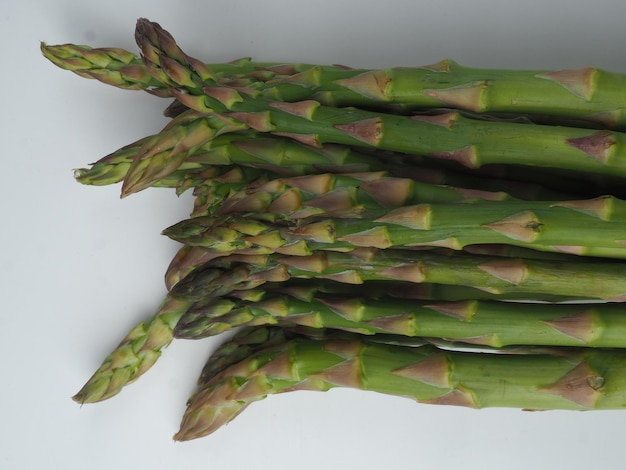 A bunch of asparagus is shown on a white surface.