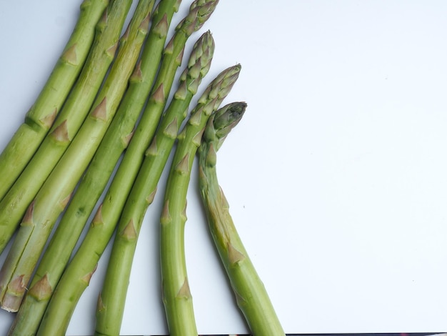 Foto un mazzo di asparagi è su una superficie bianca.