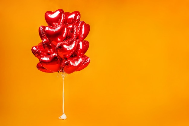 A bunch of balloons. Red hearts on an orange background.