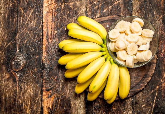 Bunch of banana slices in a bowl. On wooden table.