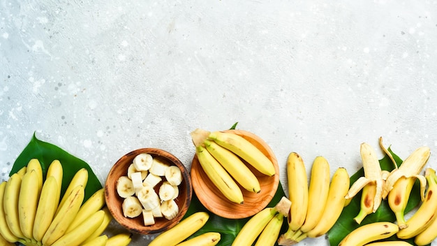 A bunch of bananas and a sliced banana baby on a table delicious natural on a stone background free copy space top view