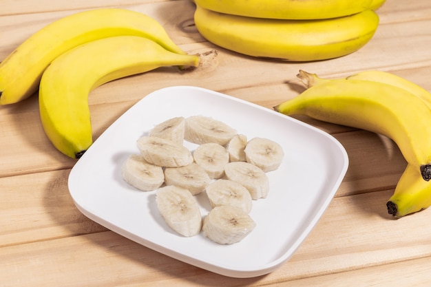 Bunch of bananas and sliced bananas on wooden table