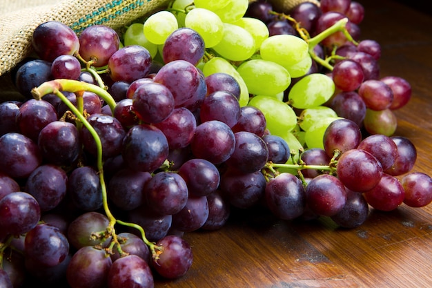 Bunch black and green grapes on wooden background