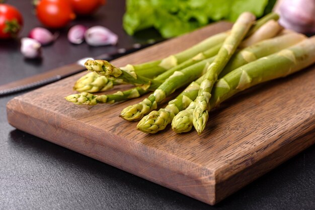 A bunch of branches of fresh green raw asparagus on a wooden cutting board