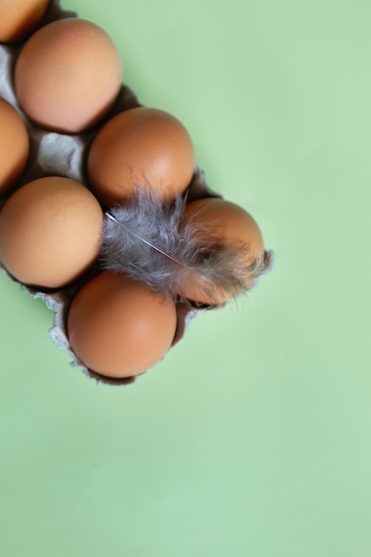 A bunch of brown eggs with a feather on the top