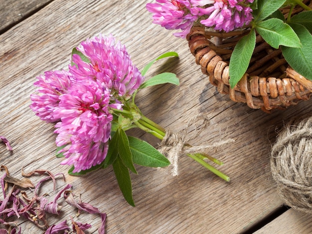 Bunch of clover and basket with flowers top view