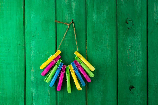 A bunch of colored plastic clothespins hanging from a wooden fence.