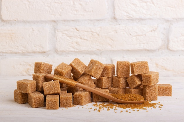 A bunch of cubes of cane sugar and sugar sand in a wooden spoon