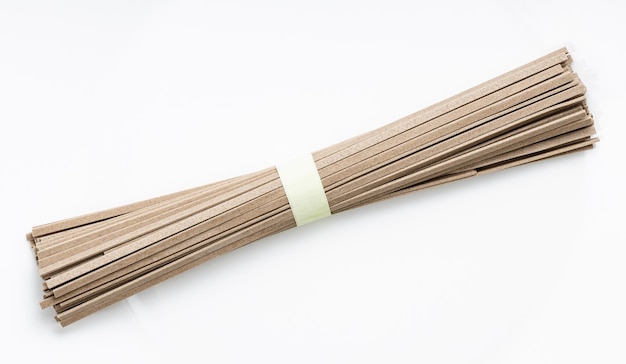 Bunch of dried flat Soba noodles on white plate