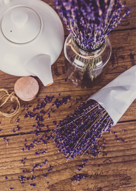 Bunch of dry cut lavender and teapot on wooden table. Top view.