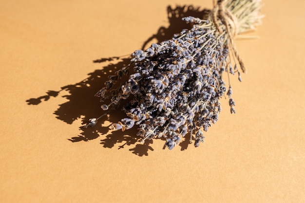 Bunch of dry lavender pounded with nattural rope on beige background. Aromatherapy and alternative medicine.