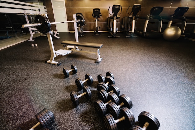 Photo bunch of dumbbells and bench press machine