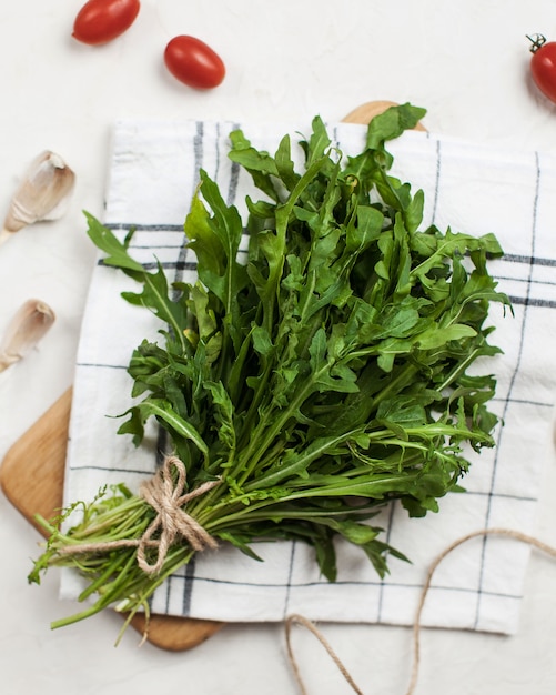 Bunch of fresh arugula closeup with cherry tomatoes and garlic on kitchen towel