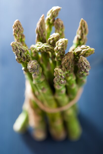 Bunch of fresh asparagus on blue background