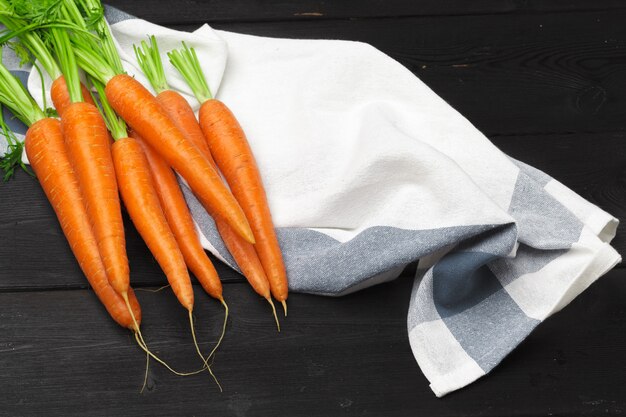 Bunch of fresh carrots with green leaves on wooden table