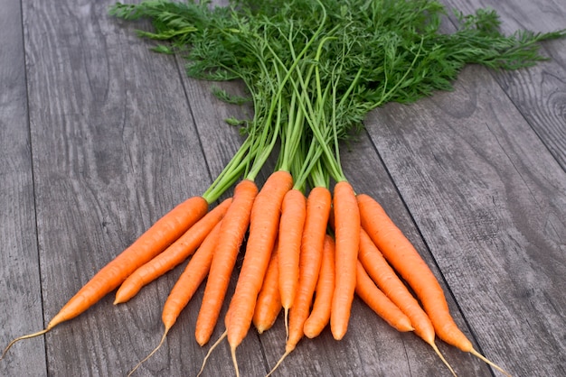 Bunch of fresh carrots on wooden background.