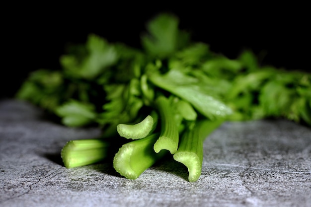 A bunch of fresh celery stalks on a concrete table.