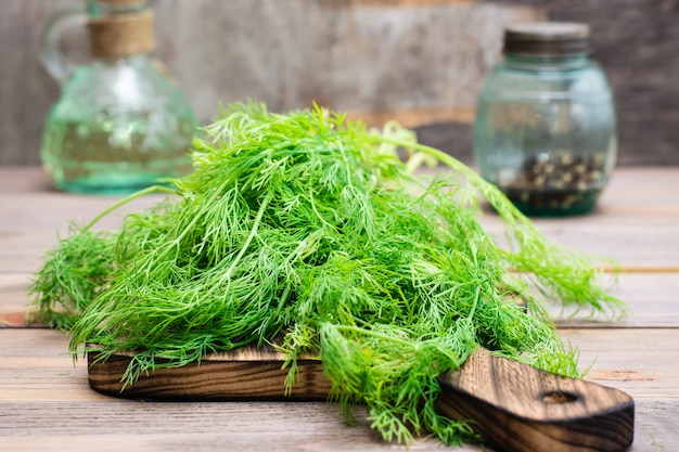 A bunch of fresh dill on a cutting board on a wooden table