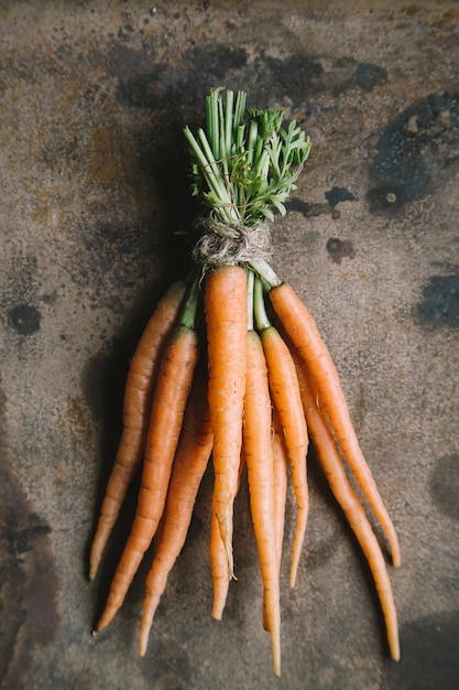 Foto mazzo di carote fresche del giardino su fondo arrugginito
