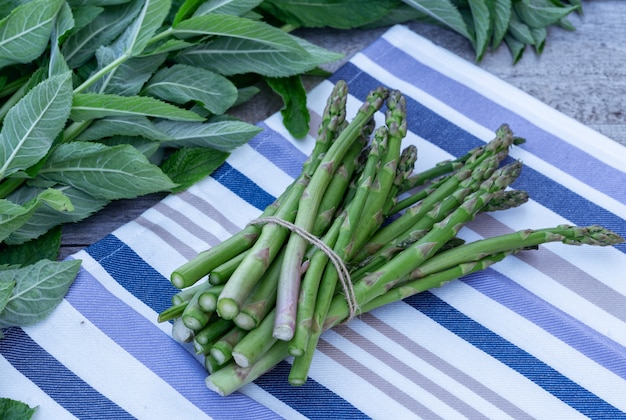 Bunch of fresh green asparagus spears on wooden table outdoor.