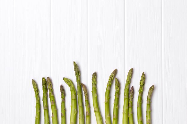 Bunch of fresh green asparagus on white wooden table table.