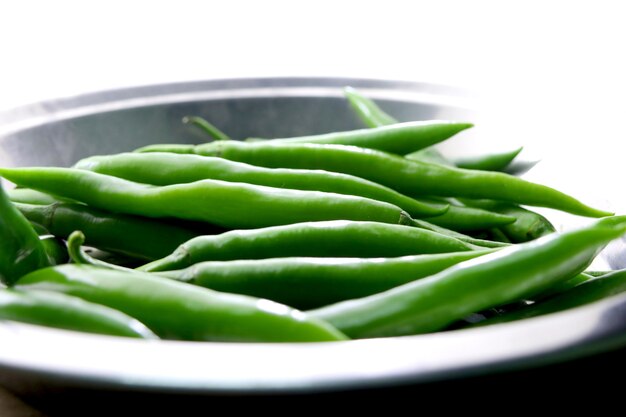 Bunch of fresh green chili peppers on a white background