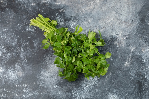 Bunch of fresh green parsley placed on a marble table . 