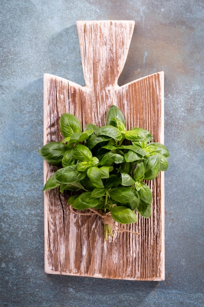 Photo bunch of fresh organic basil in cutting board