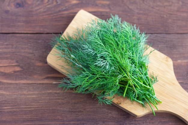 A bunch of fresh organic dill on a wooden background.