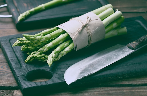 Bunch of fresh raw asparagus on a wooden black kitchen board