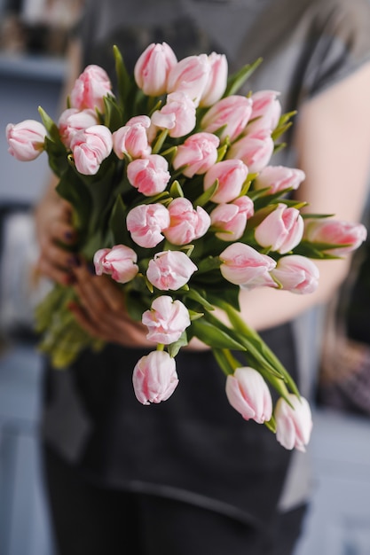 Bunch of fresh spring pink tulips in hand, copy space