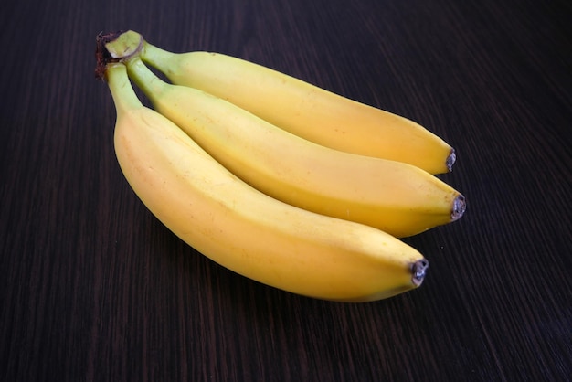 Bunch of fresh tasty bananas on black wooden background closeup