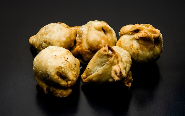 A bunch of fried samosas on a textured dark background