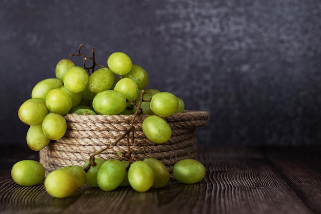 A bunch of grapes in a handmade basket on a dark background