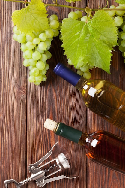 Букет винограда, бутылки белого вина и штопор