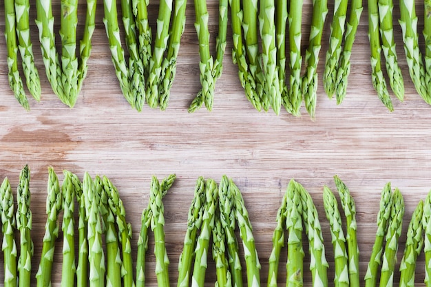 Photo bunch of green asparagus on wooden board with copy space