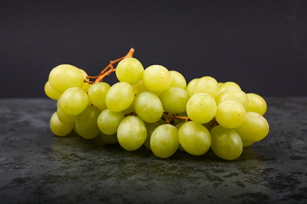 A bunch of green grape on a marble dark marble.