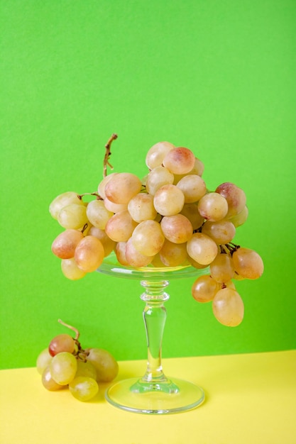 A bunch of green grapes on a pedestal on a green background