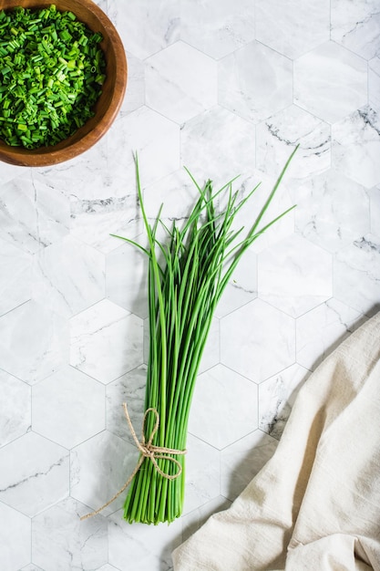 A bunch of green onions and fresh chopped green onions in a\
wooden bowl on the table