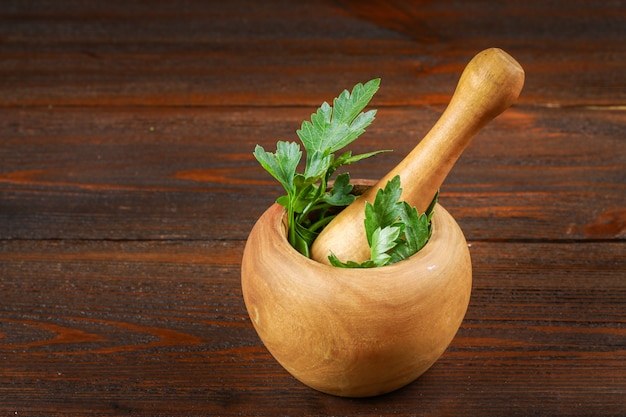 A bunch of green parsley on a wooden table in a mortar