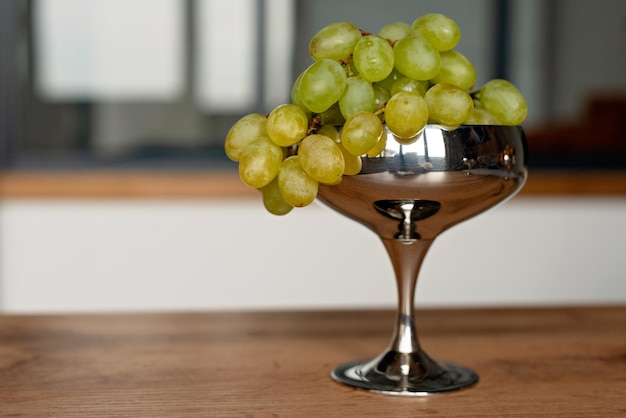 A bunch of green ripe grapes in a metal bowl on a wooden table Food healthy eating Soft selective focus