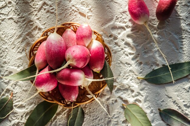 a bunch of homemade radishes lies on the table vegetables red and green on a light background