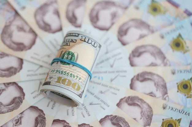 Bunch of hundred us dollar bills lies on many banknotes of ukrainian hryvnias economical default