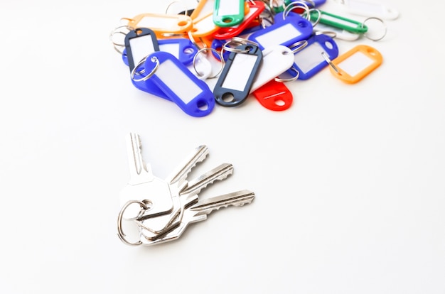 A bunch of keys with key chains of different colors and a place for an inscription on a white background