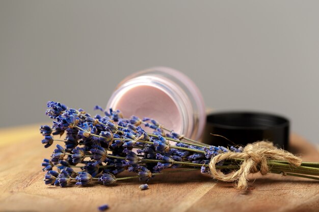 Bunch of lavender and cosmetic pot on a wooden table