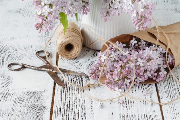 Bunch of lilac flowers in paper cone on purple wall