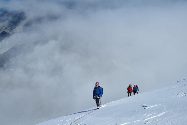 Bunch of mountaineers climbs or alpinists to the top of a snow-capped mountain