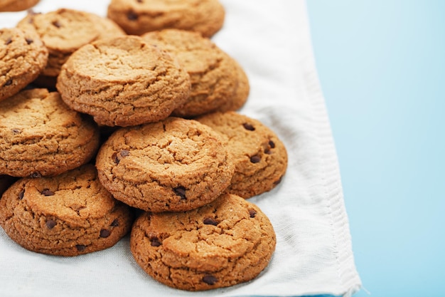 A bunch of oatmeal cookies with chocolate on a napkin on a blue background. Top view, free space