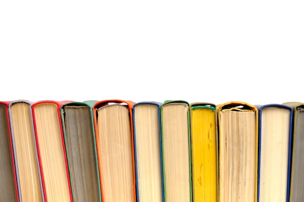 Куча старых потрепанных разноцветных книг в твердом переплете на белом фоне