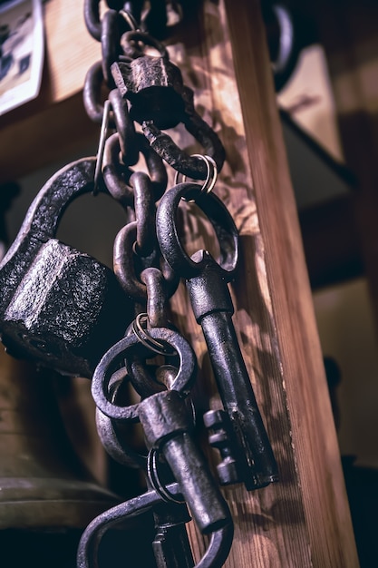 Photo a bunch of old metal keys hanging on dark wooden background, close up, copy space. secret symbol or secret symbol.